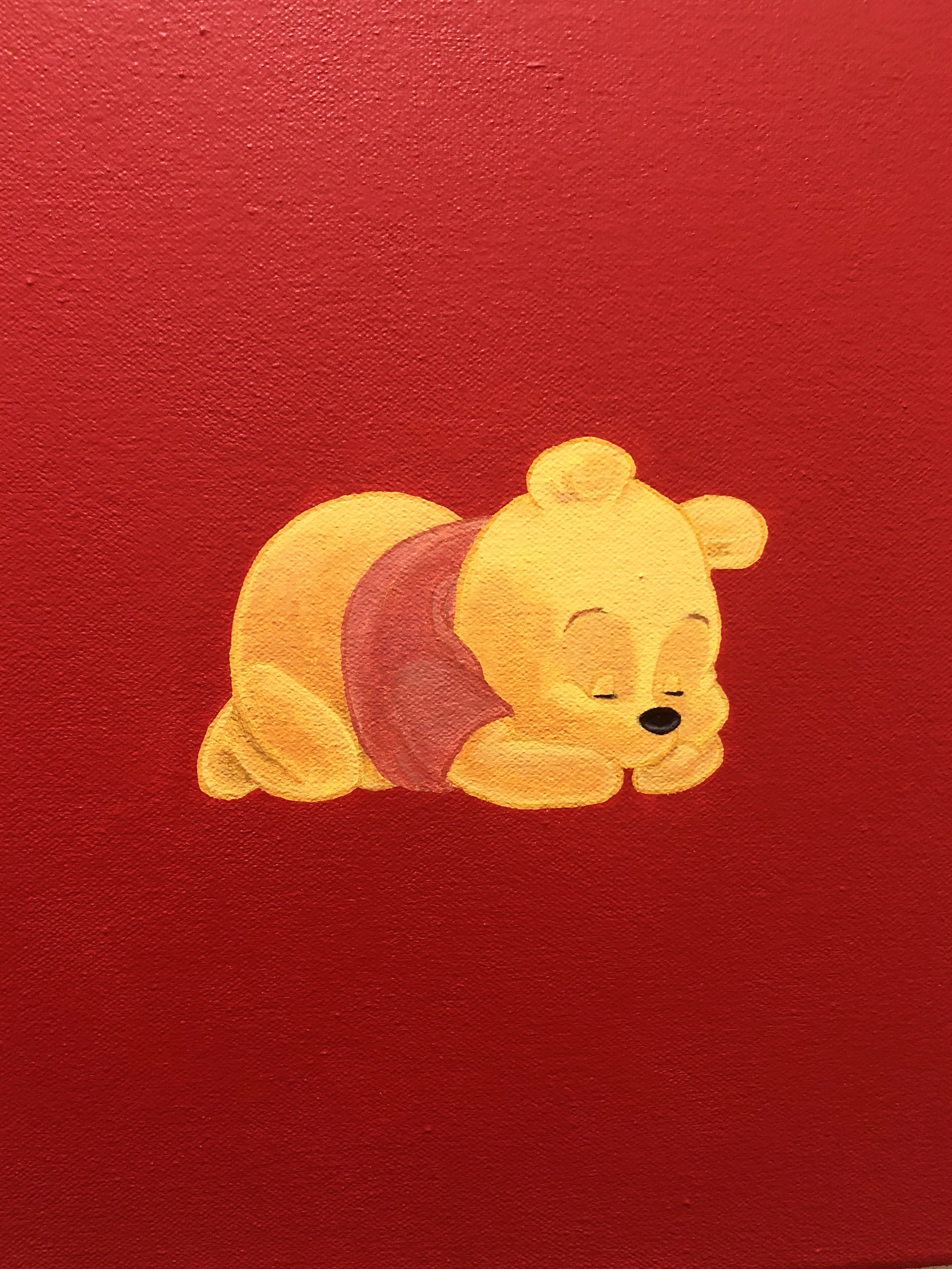 Detail of a painting of winnie the pooh lying asleep on a red background hung on a white wall